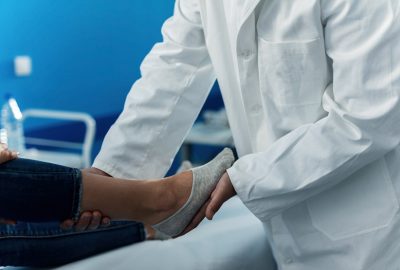 Close up of orthopedic examining foot of a woman at doctor's office.